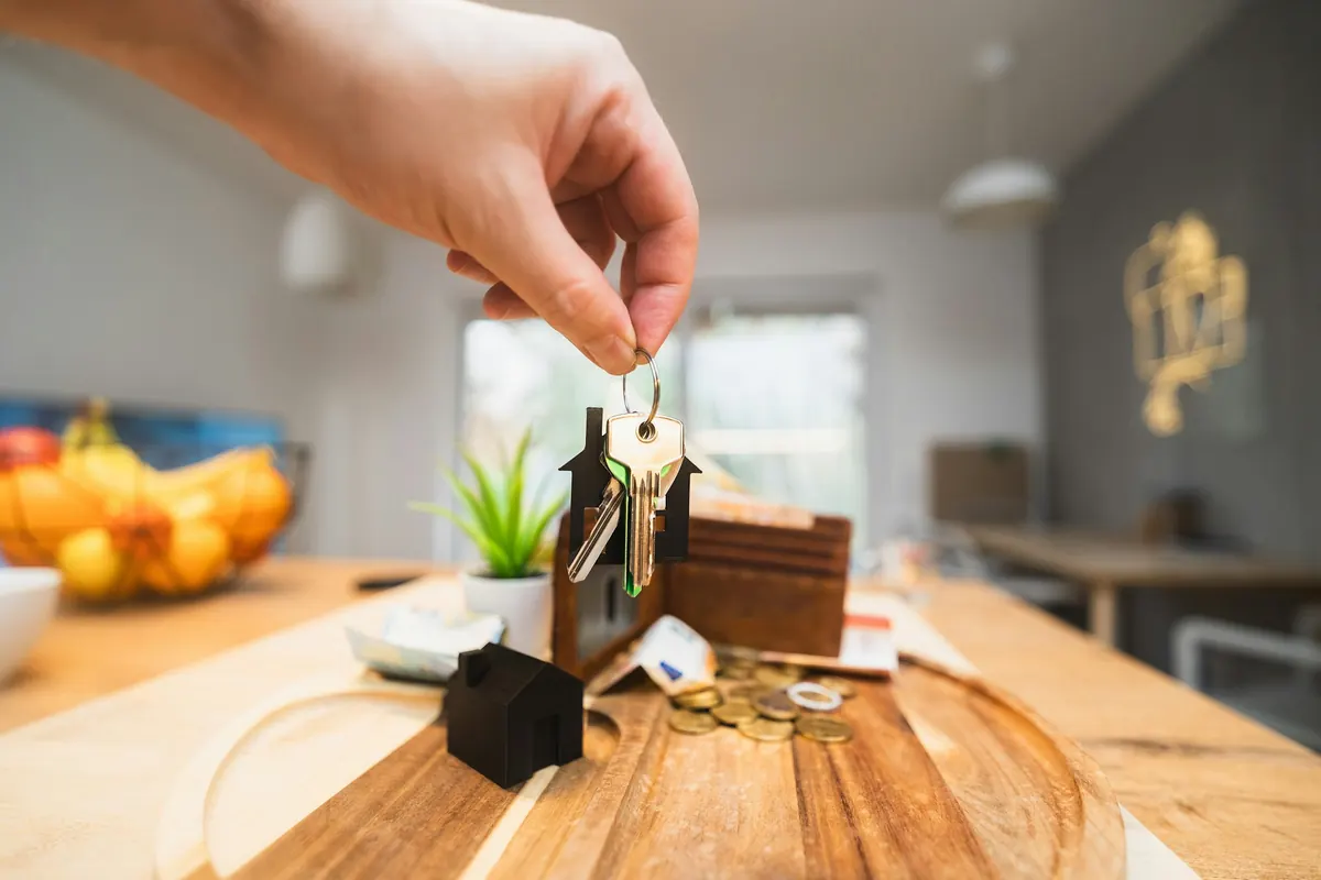 Main tenant les clés d’un appartement au-dessus d’une table de salon