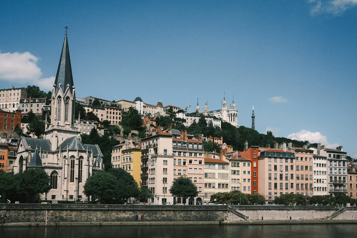 Façades colorées et clocher au bord de l’eau à Lyon, sous un ciel bleu