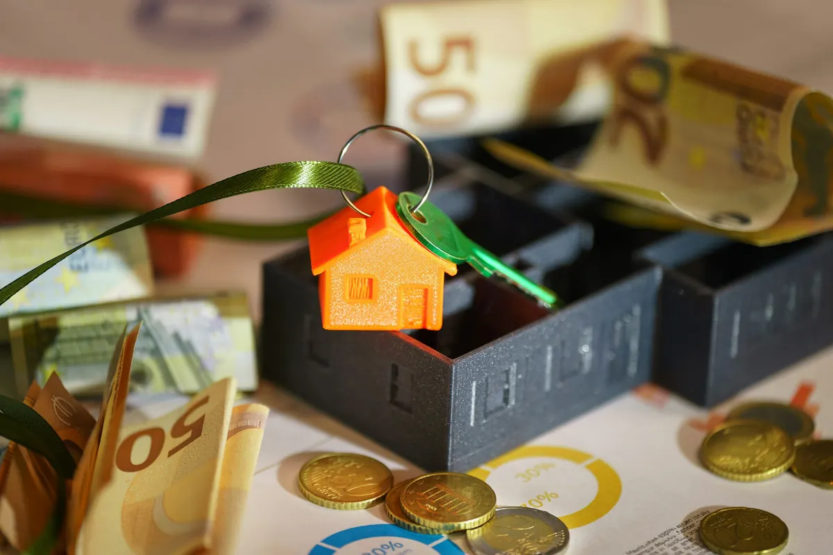 Clés d’un logement avec un porte-clés maison, billets et pièces