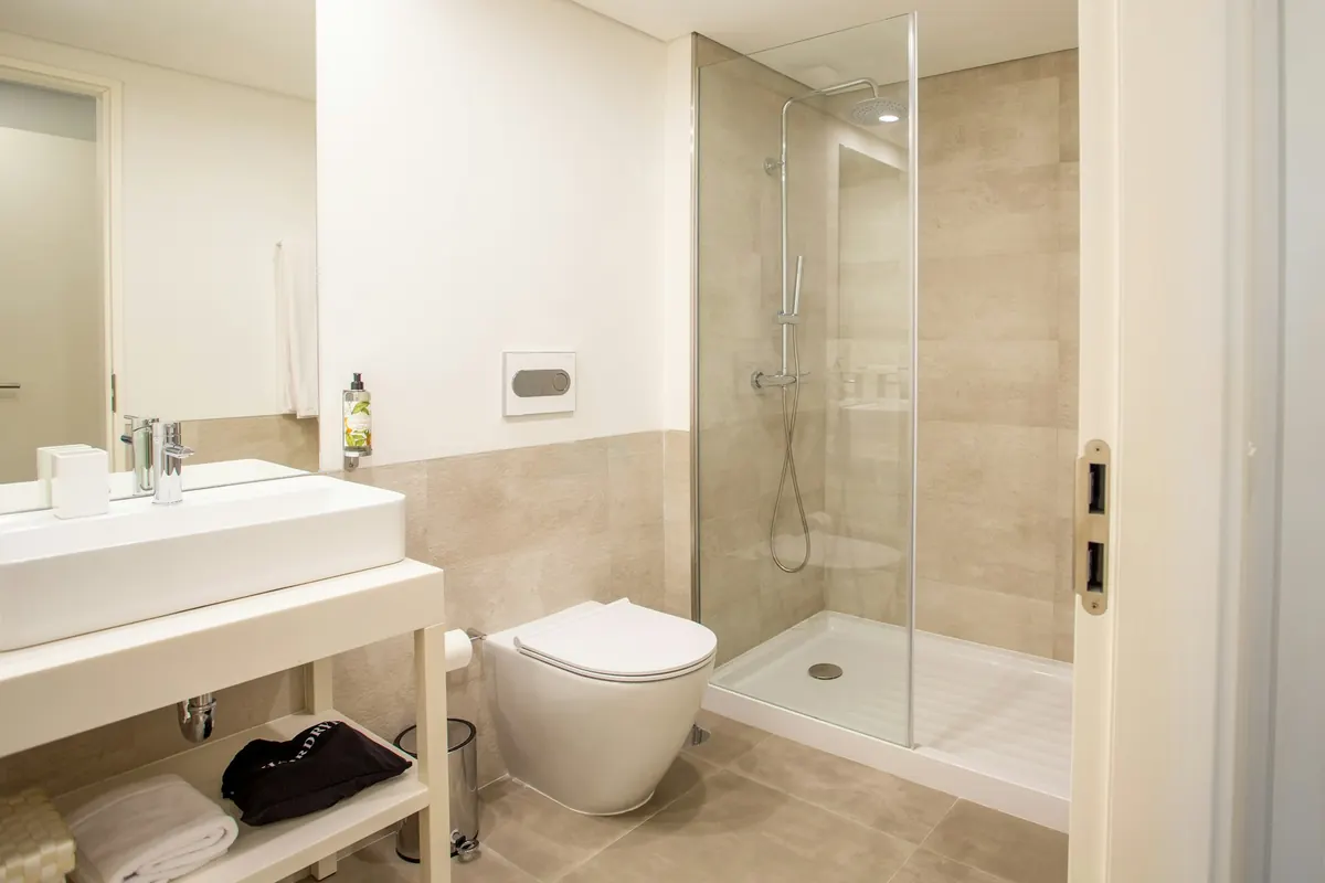 Salle de bain propre avec douche vitrée et serviettes à disposition